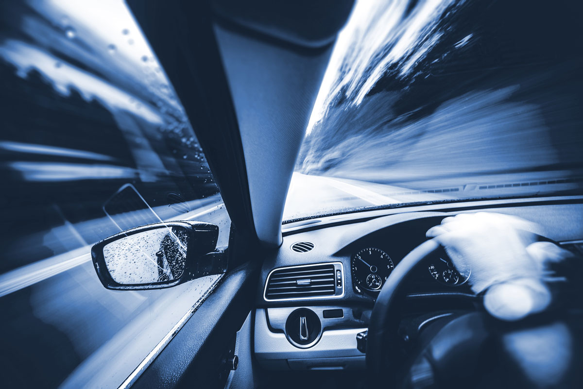 driver view of road with blurry hand on steering wheel