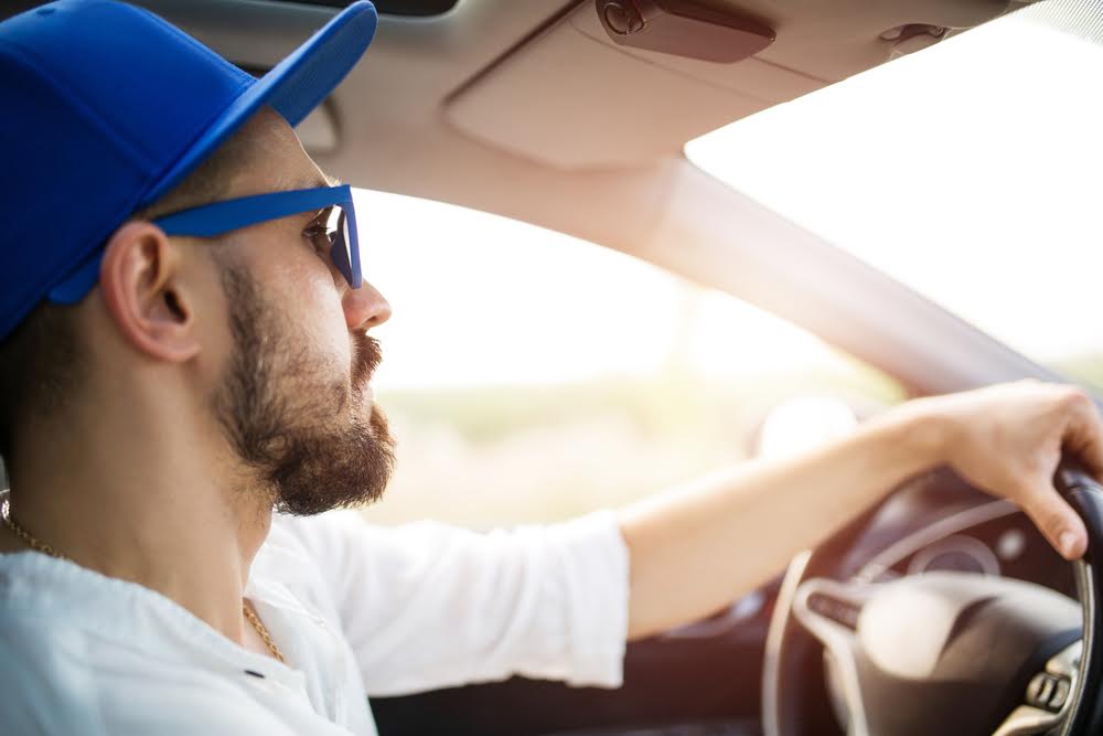 jeune homme avec une casquette bleue dans son auto