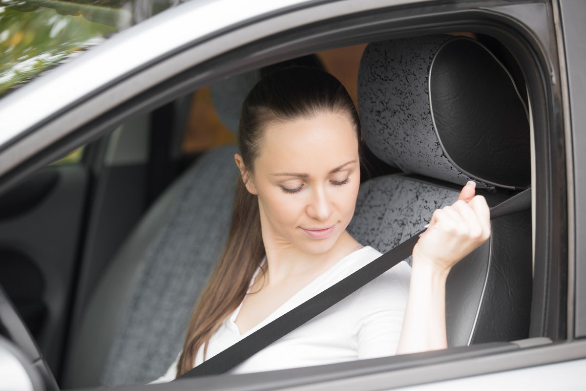 female in car putting a seatbelt