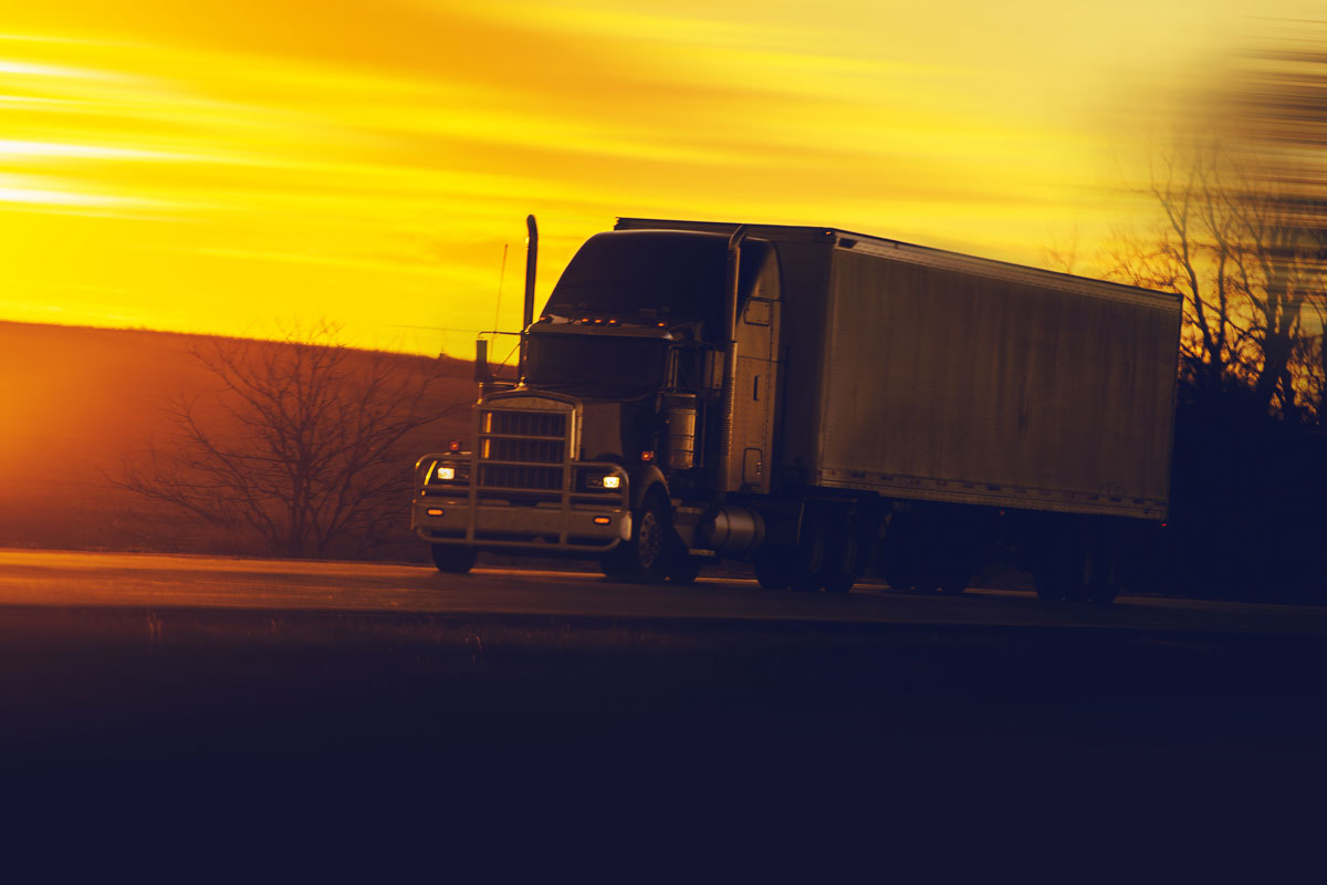 camion 18 roues qui roule sur la route devant le coucher du soleil